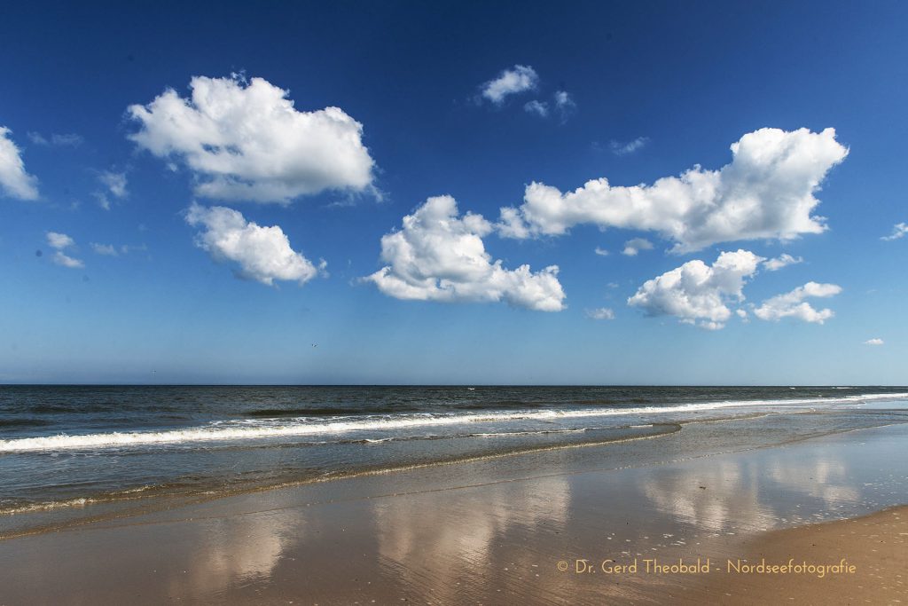 Cumuluswolken spiegeln sich am Spülsaum des Nordstrands von Borkum